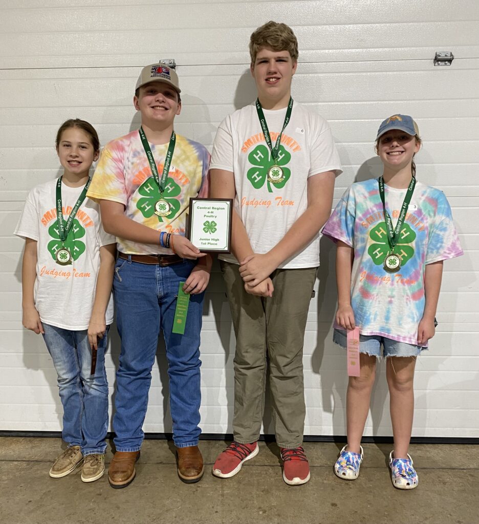 A group of four 4-H'ers show off their ribbons, medals, and a 1st place plaque